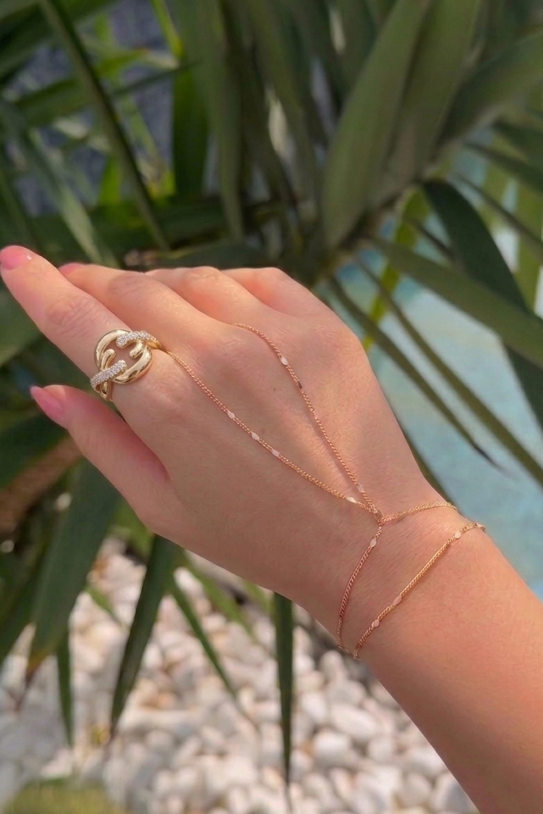 Hand wearing a gold ring and gold handchain