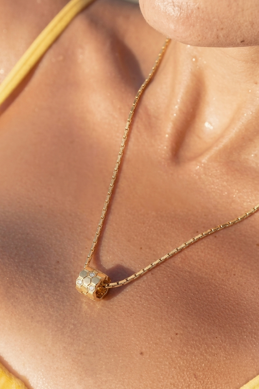 Gold necklace with a small pendant on a person's neck